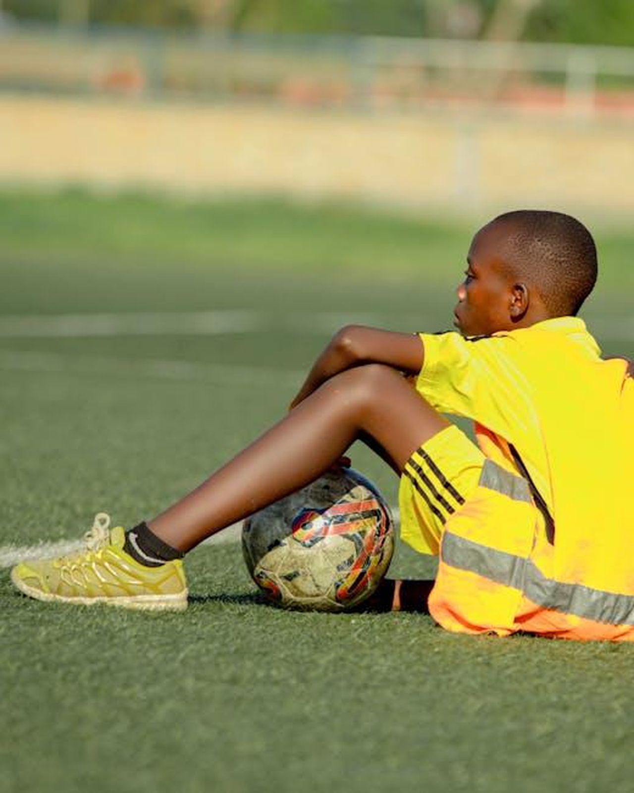 Giron_infortunato_contro_il_Monopoli_spazio_a_Groppelli_ZNbGzvtNct - Confidenze24 Source: Chris wade NTEZICIMPA - pexels - A young soccer player in a yellow jersey takes a break on the grass field with a soccer ball.