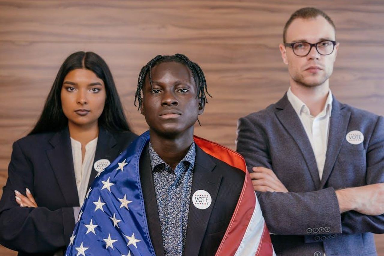 Gli_altri_partiti_39OHlvQ0dz - Confidenze24 Source: Mikhail Nilov - pexels - Three professionals with 'Vote' buttons, emphasizing diversity and electoral participation.