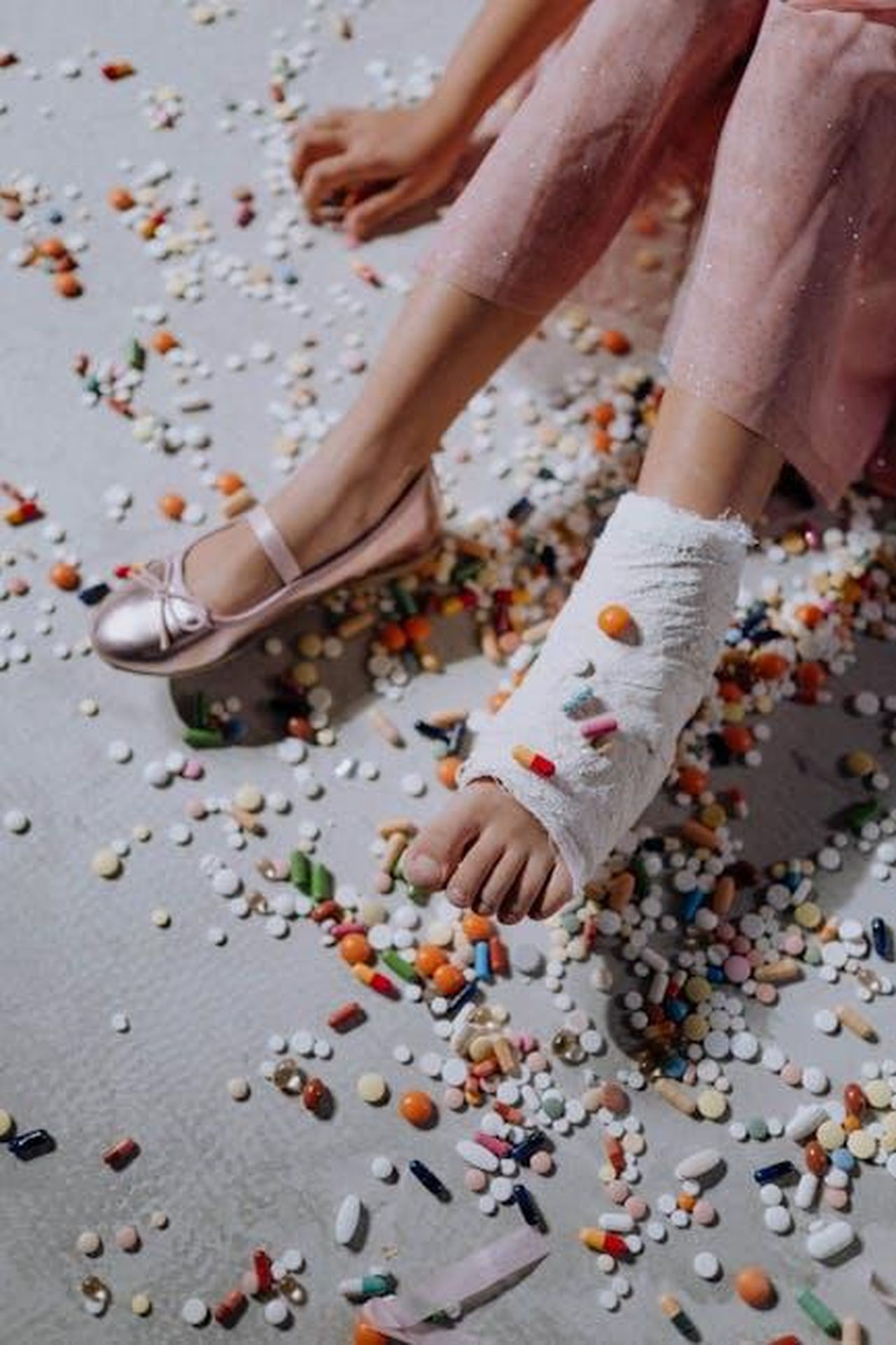 Grande_Fratello_crisi_tra_Mariavittoria_e_Tommaso_per_Alfonso_ctSfeQh6bF - Confidenze24 Source: cottonbro studio - pexels - Close-up of a child's bandaged foot amidst colorful scattered pills on the floor.