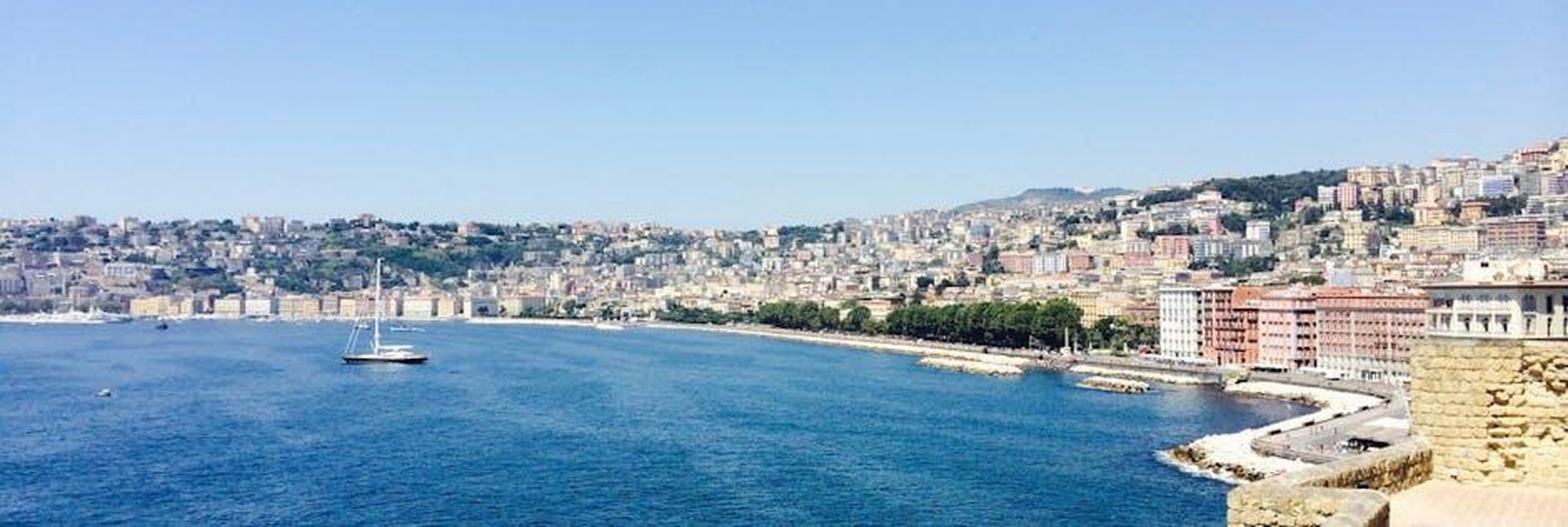 Guido_torna_a_Napoli_e_fa_i_conti_con_unamara_realt_anticipazioni_Un_posto_al_sole_del_262_43ryzZBXW3 - Confidenze24 Source: Samuel Walker - pexels - Panoramic view of Naples cityscape along the coastline with sailboats on a sunny day.