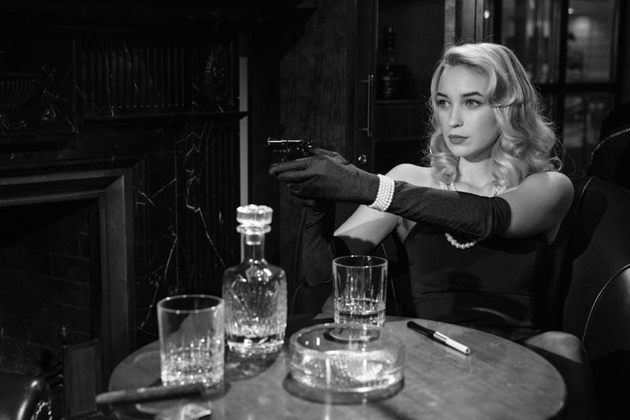 Helene_scopre_il_tradimento_di_Andr_2EMPA45sLG - Confidenze24 Source: cottonbro studio - pexels - Elegant femme fatale holding a handgun, creating a vintage noir atmosphere indoors.