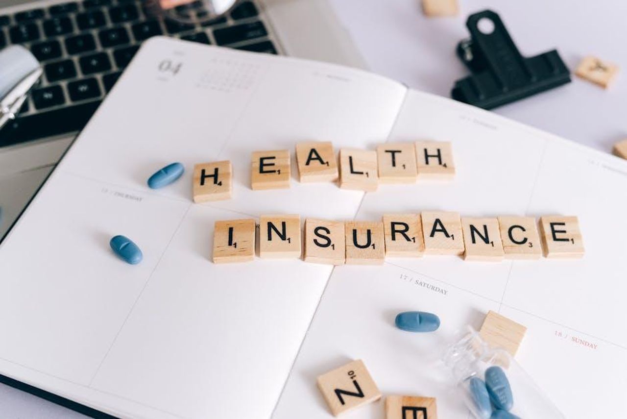ITV_fornir_copertura_degli_Oscar_MXG7mYnMRX - Confidenze24 Source: Leeloo The First - pexels - Scrabble tiles spelling 'Health Insurance' on planner with pills and laptop, symbolizing healthcare planning.
