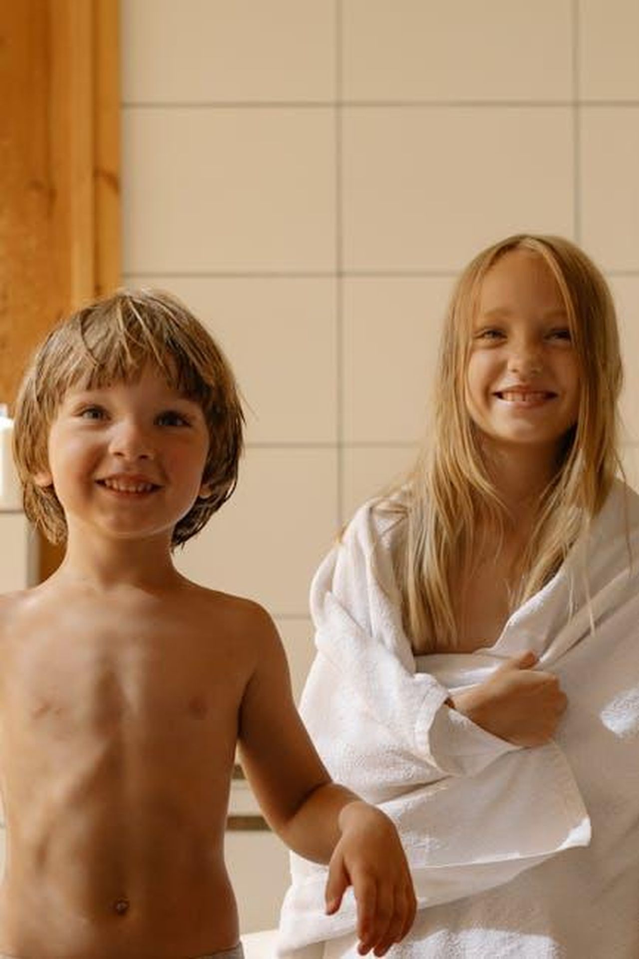 I_Sondaggi_Chi_Rischia_lEliminazione_WO81T2p1G3 - Confidenze24 Source: cottonbro studio - pexels - Two happy children in a sunlit room, wrapped in towels, enjoying a playful moment indoors.