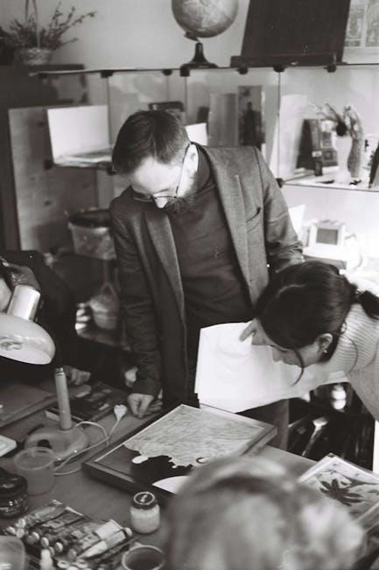 I_competenti_e_gli_approfondimenti_in_studio_mIb12bG4Xf - Confidenze24 Source: Иван Медведев - pexels - Two art specialists examining a painting in a cluttered studio setting.