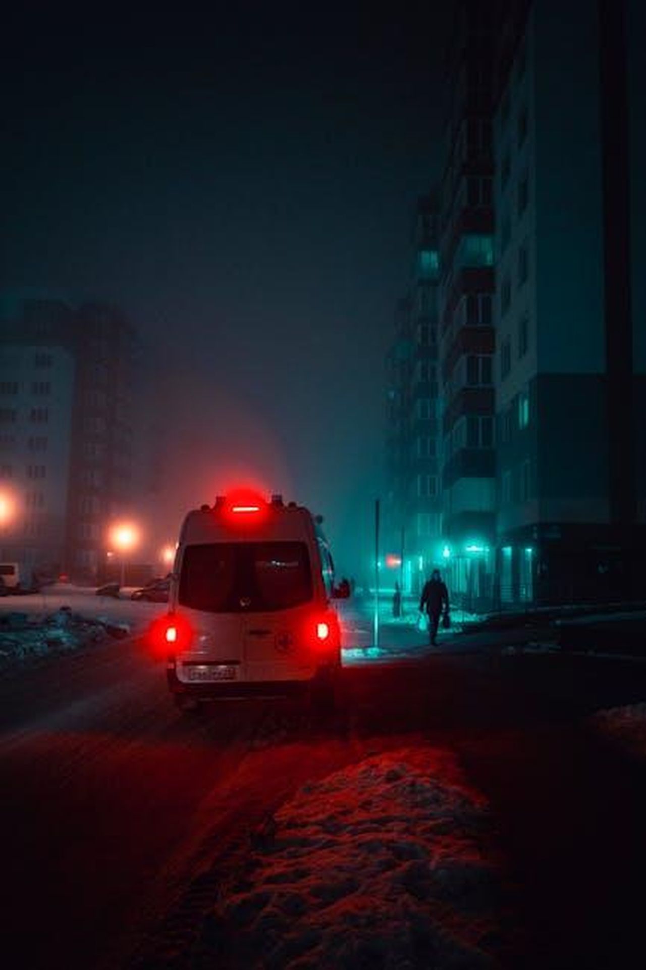 I_disperati_tentativi_di_salvarla_qlqJS06XIf - Confidenze24 Source: Artem Saranin - pexels - A moody urban night scene featuring an illuminated ambulance on a snowy street amidst tall buildings.