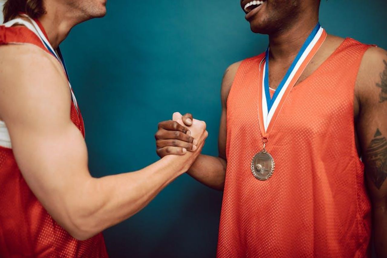 I_fan_esprimono_il_loro_supporto_p8LdqJEYNB - Confidenze24 Source: RDNE Stock project - pexels - Two basketball players in red jerseys celebrating with a handshake and medals.