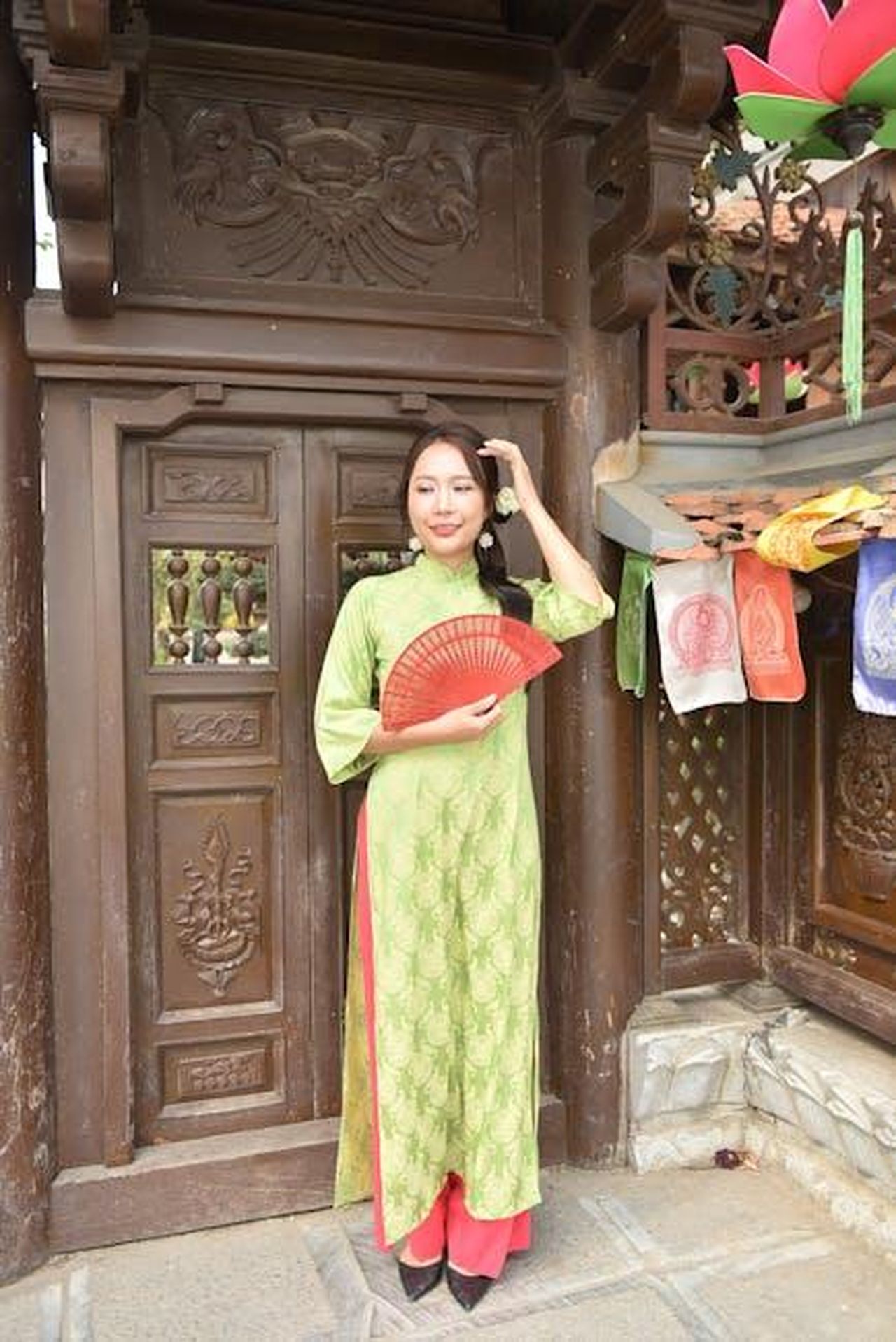 I_fan_minacciano_di_smettere_di_guardare_lo_show_a_causa_della_trama_sul_cancro_di_Julie_9K2fzvKDBP - Confidenze24 Source: Felix Young - pexels - Woman in green traditional dress with red fan at ornate temple doorway.