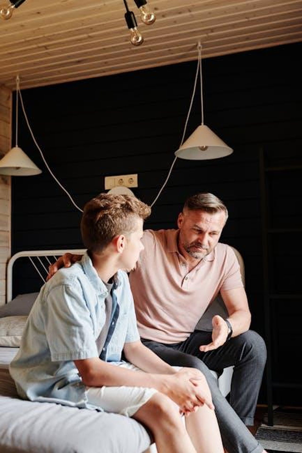 I_funzionari_reali_seguono_i_passi_di_Meghan_YYuirAN9Vk - Confidenze24 Source: Julia M Cameron - pexels - Father and son having a meaningful talk in a cozy bedroom setting.