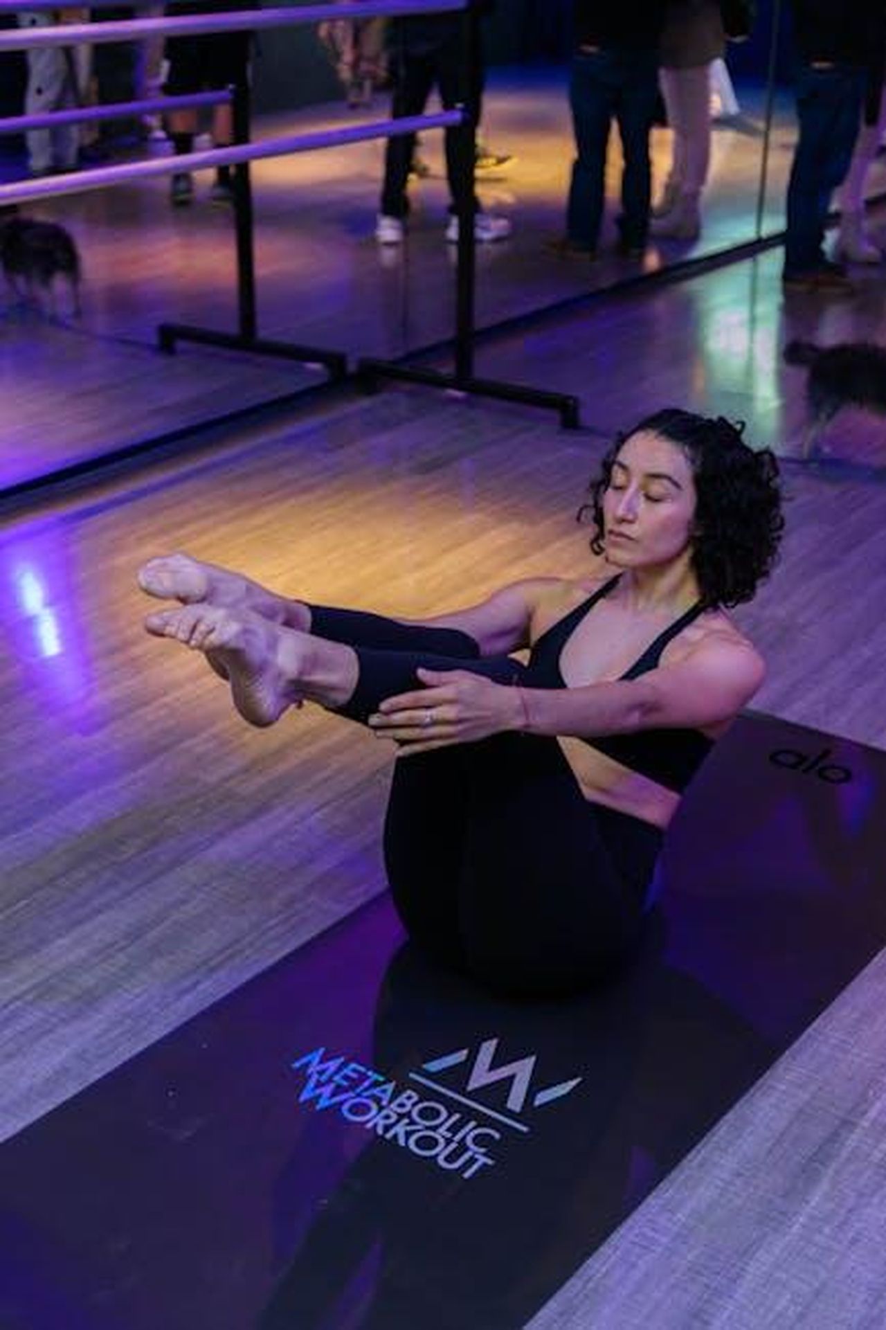 I_migliori_set_in_Spruce_Green_da_acquistare_d5FhMri52U - Confidenze24 Source: Ali Alcántara - pexels - Woman in black sportswear practicing yoga on mat in gym. Reflective mirror background adds depth.