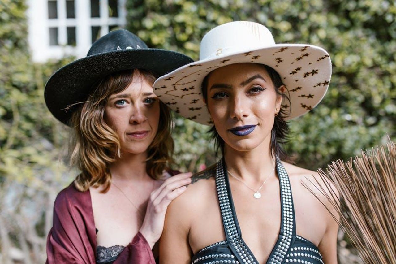 I_primi_segni_dello_zodiaco_3VBeZqTc4W - Confidenze24 Source: RDNE Stock project - pexels - Two women wearing fashionable hats pose confidently in a garden setting.