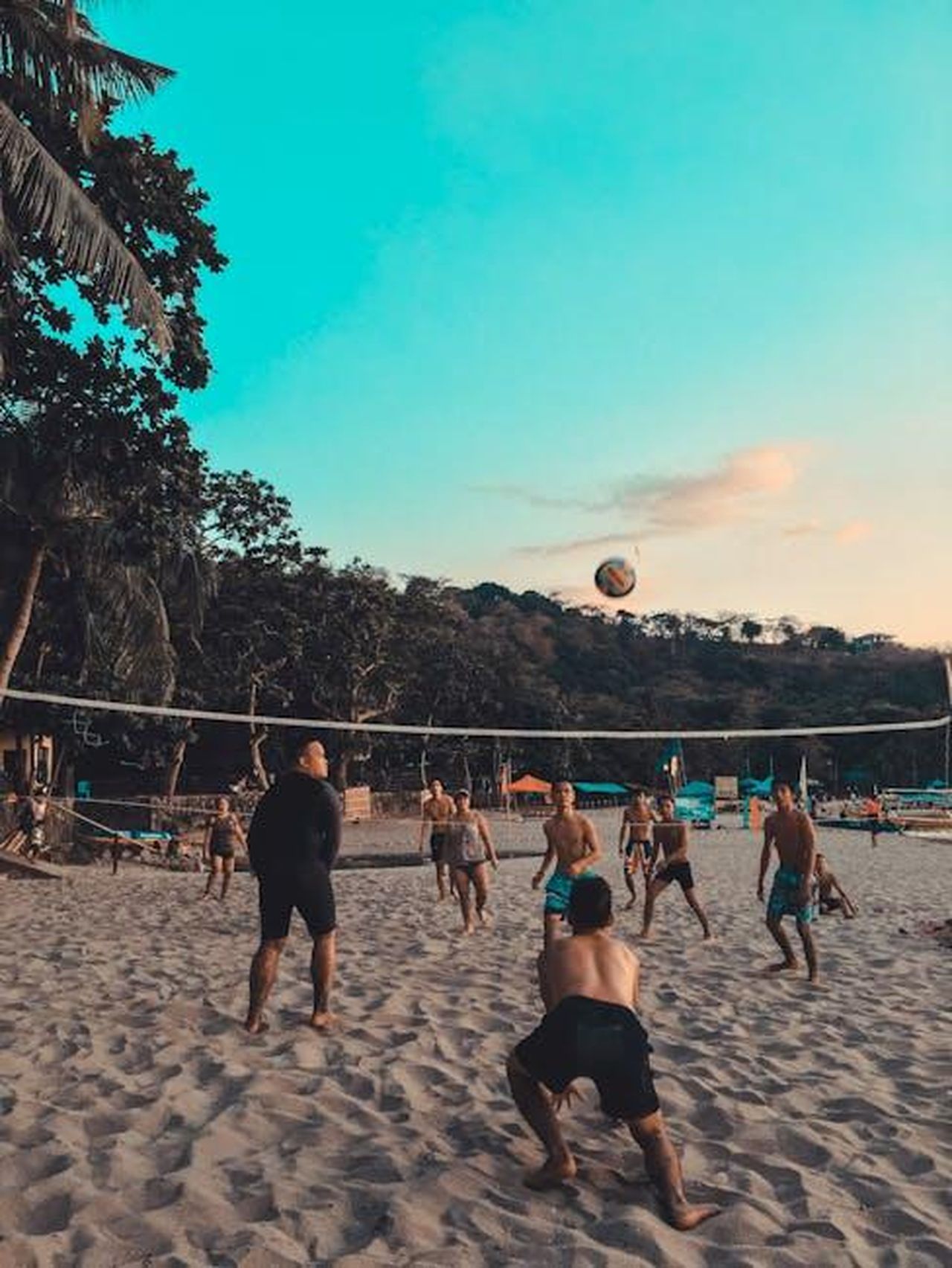 Il_blocco_azzurro_della_nazionale_italiana_resta_in_Italia_XChqrujYrT - Confidenze24 Source: Jeff Ibera - pexels - A vibrant scene of friends playing beach volleyball at sunset with scenic views.