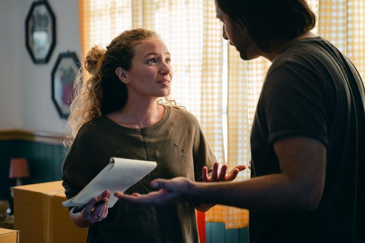 Il_confronto_acceso_e_le_accuse_reciproche_rNq261Xin4 - Confidenze24 Source: Ketut Subiyanto - pexels - A couple talking in their living room surrounded by moving boxes, planning their new home setup.