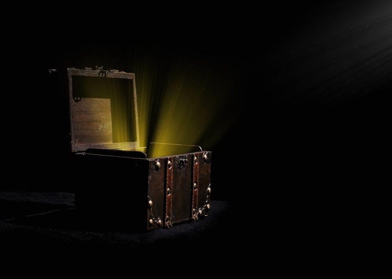 Il_contenuto_della_scatola_6lRbqTMqRG - Confidenze24 Source: David Bartus - pexels - Open wooden chest emitting a mysterious glowing light in a dark room.