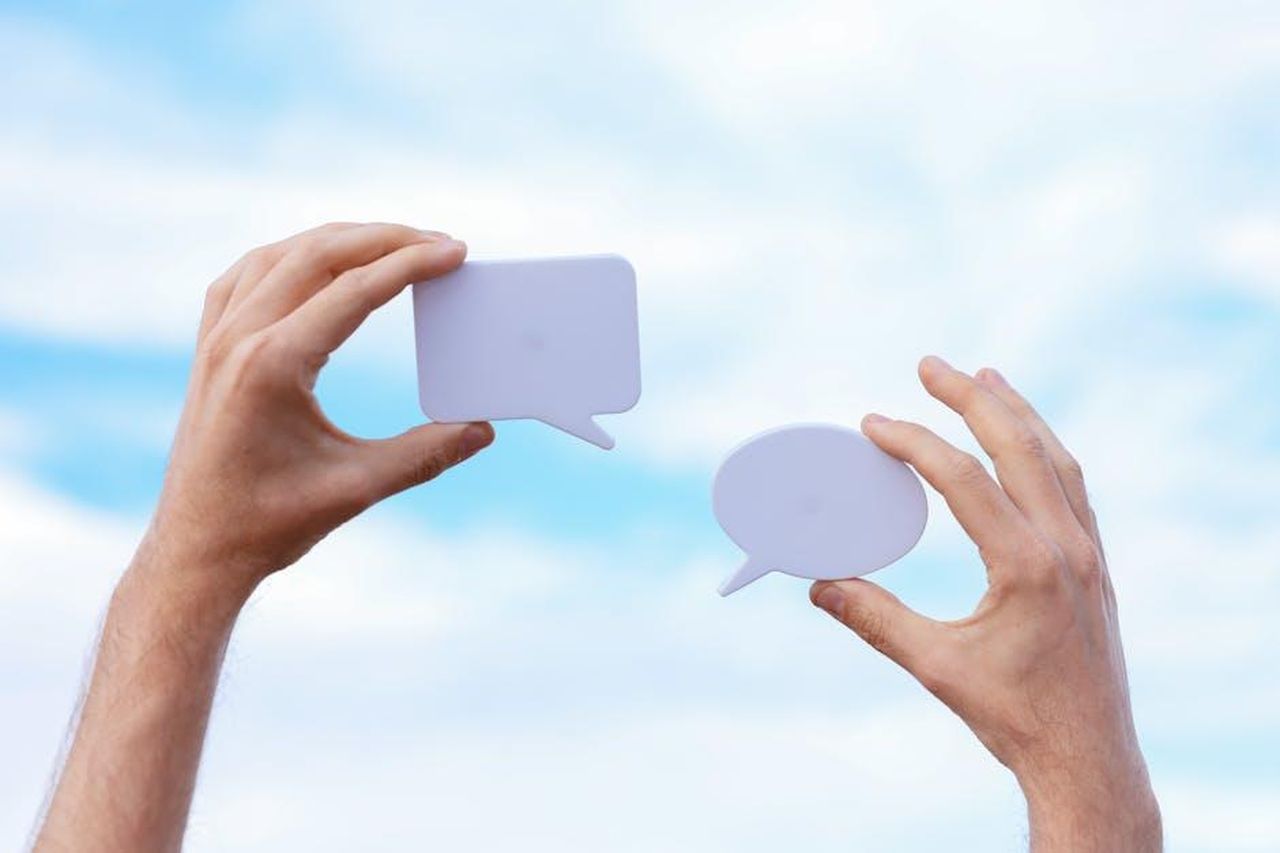 Il_dibattito_sui_social_8mImd7otWU - Confidenze24 Source: Cup of Couple - pexels - Close-up of hands holding speech bubbles, symbolizing communication and dialogue against a blue sky.