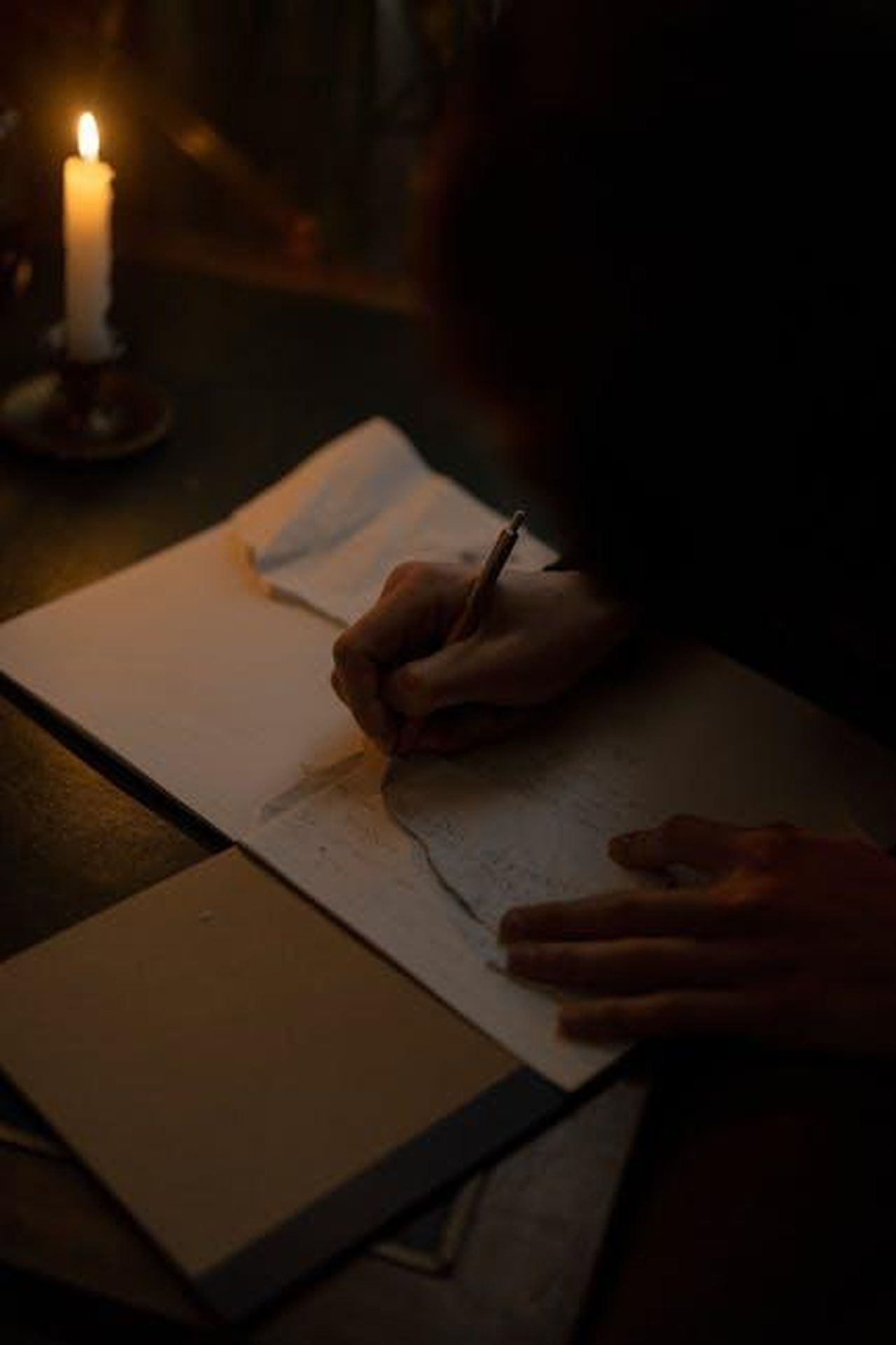 Il_libro_di_memorie_di_Paulina_No_Filter_D3kH6OvfNw - Confidenze24 Source: cottonbro studio - pexels - A person writes in a notebook by candlelight creating a dark and focused atmosphere.