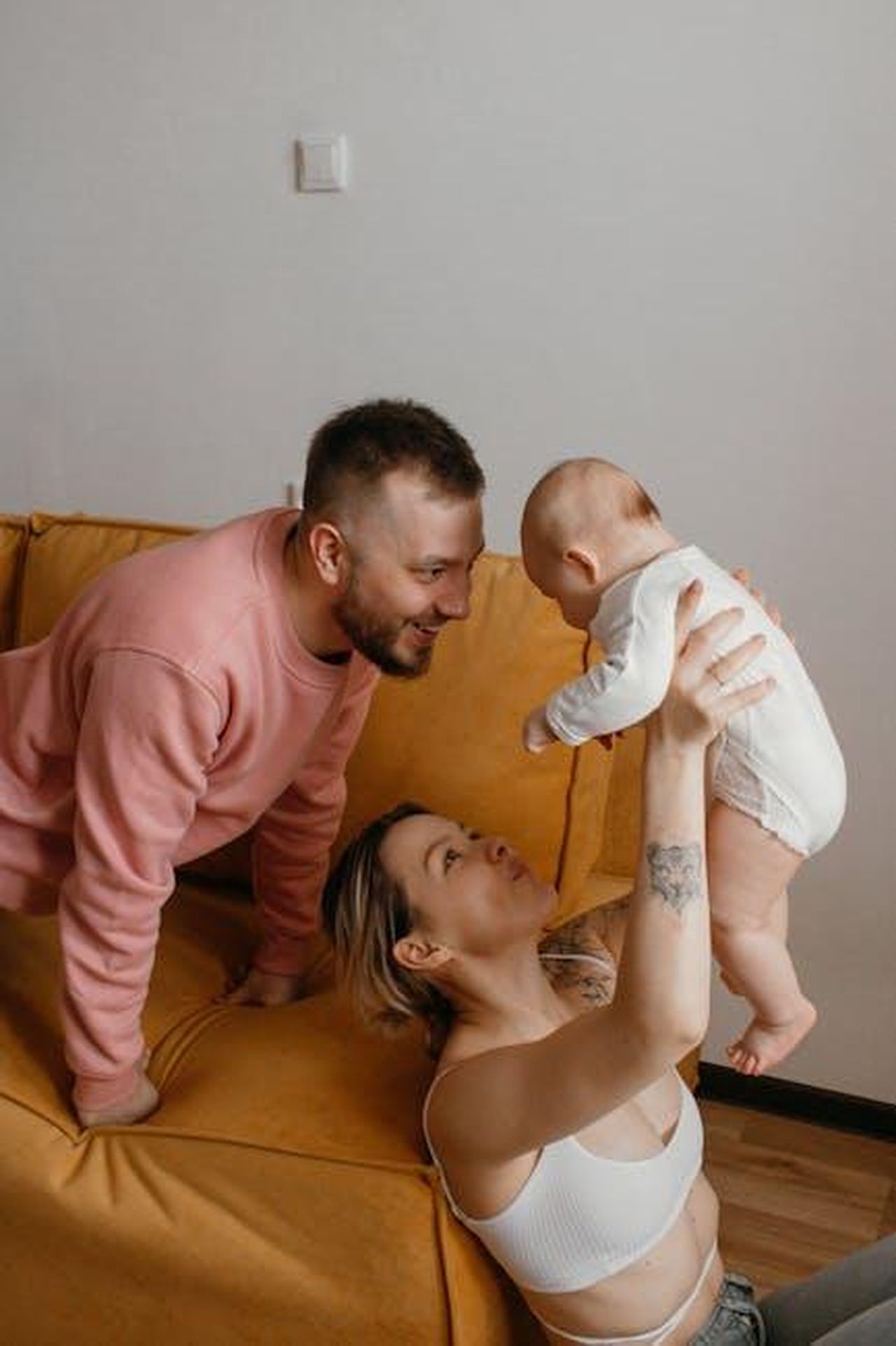 Il_momento_della_riappacificazione_Pp5Sgyh20W - Confidenze24 Source: Olya Afanasyeva - pexels - A happy family scene with parents playing with their baby indoors, showcasing love and togetherness.