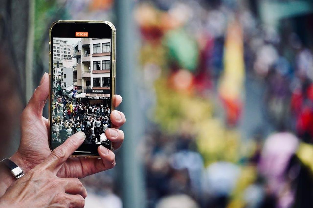 Il_parere_degli_spettatori_B3hx4eiWsa - Confidenze24 Source: Tuan Vy - pexels - A vibrant street parade captured on a mobile phone, showcasing urban life.