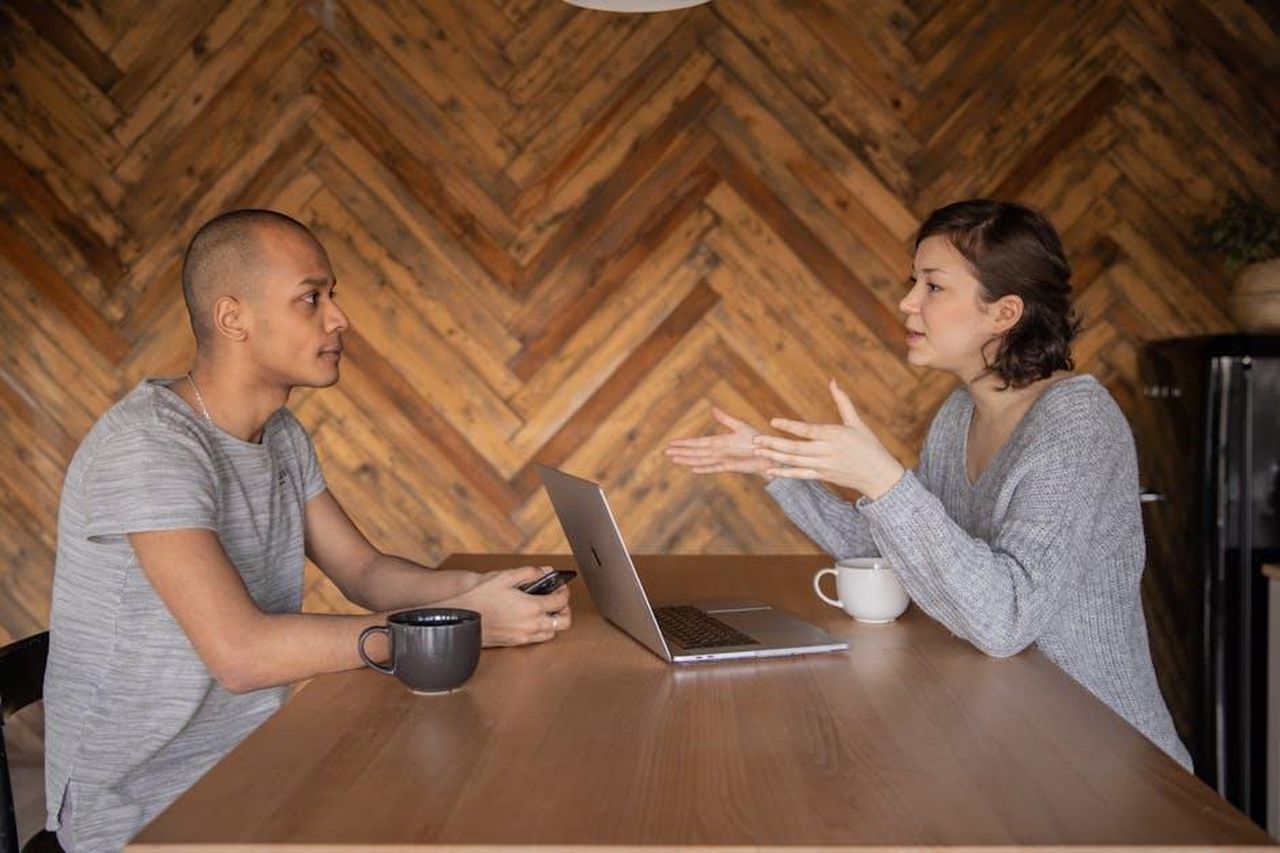 Il_parere_degli_spettatori_h0FgpyCc4d - Confidenze24 Source: KATRIN BOLOVTSOVA - pexels - Focused woman explaining opinion to ethnic male coworker during business teamwork sitting at table with laptop and coffee cups in cozy kitchen against wooden wall and looking at each other