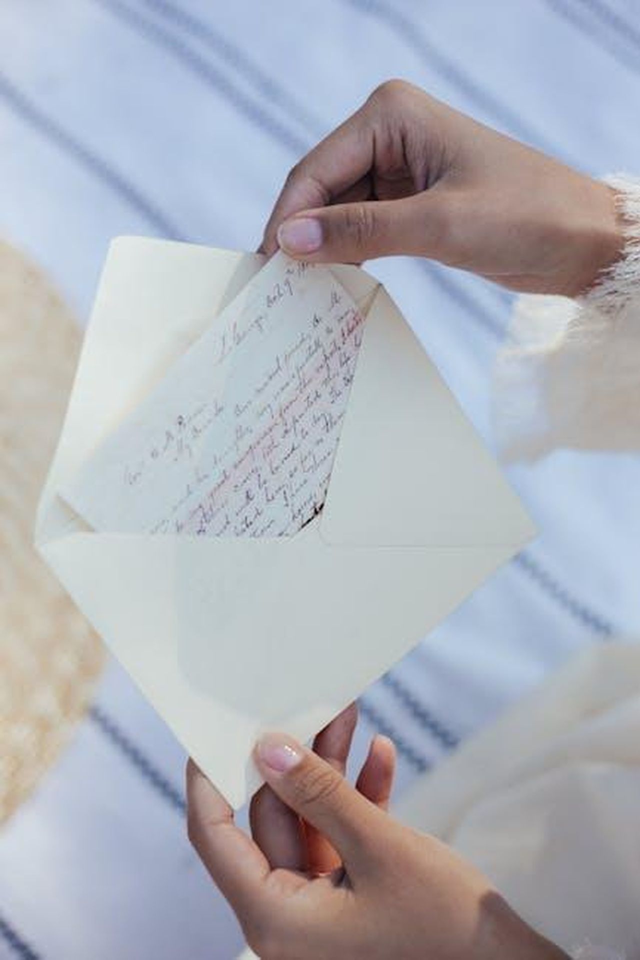 Il_passato_di_Helena_e_le_sue_insicurezze_aLA1w5pxM9 - Confidenze24 Source: Ron Lach - pexels - A woman's hands open an envelope containing a handwritten love letter, evoking nostalgia and romance.