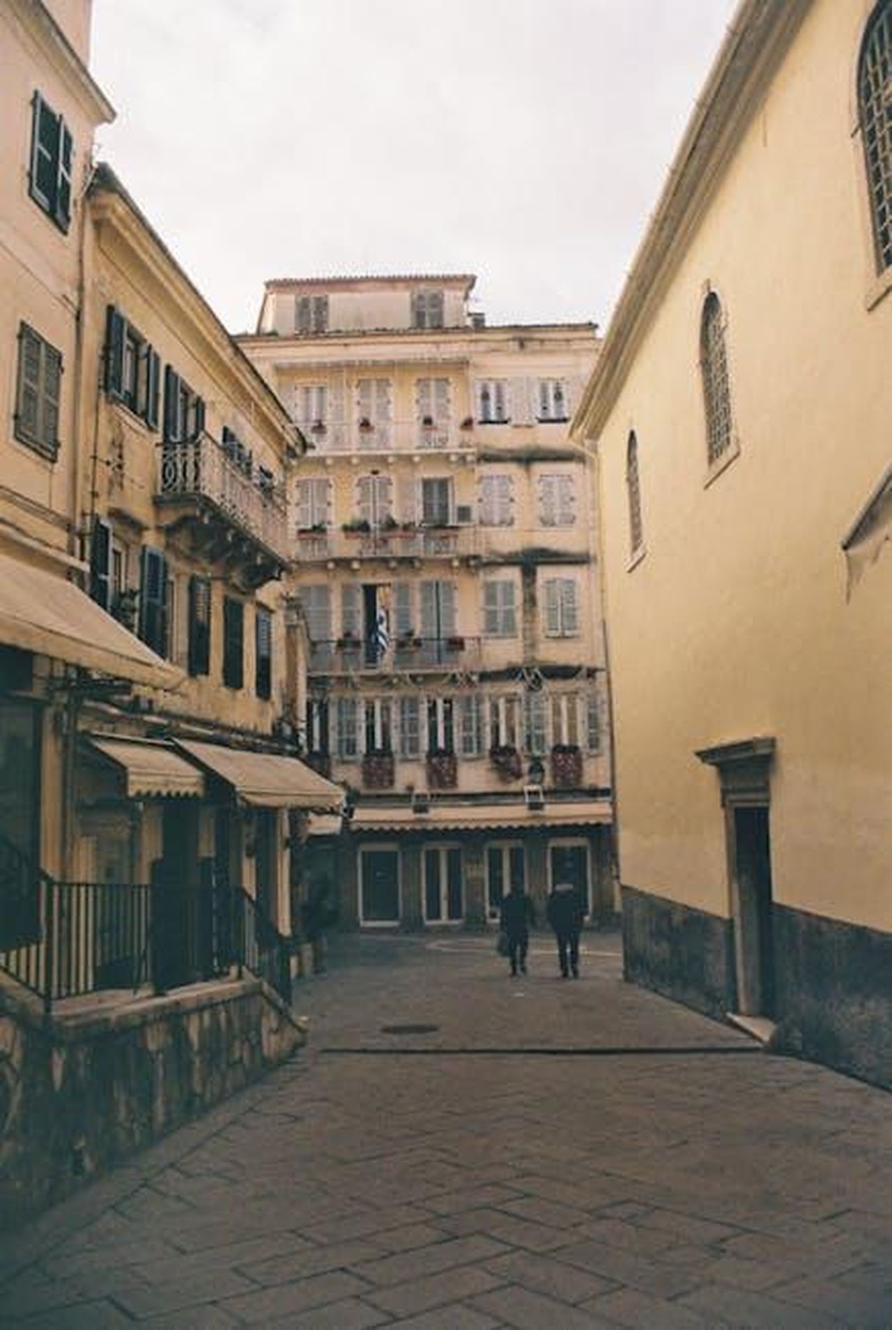 Il_ritorno_di_Yesim_in_citt_dopo_la_breve_vacanza_k1HwibIuIX - Confidenze24 Source: Marina Gr - pexels - Explore a quaint alleyway in Corfu, Greece, showcasing vintage architecture and urban charm.
