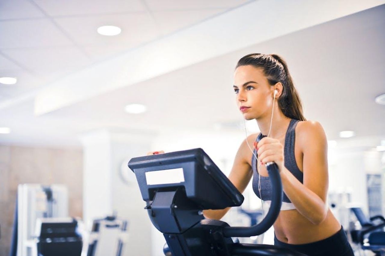 Il_ruolo_di_un_hub_fisico_nellera_dello_streaming_PoSTybQg4r - Confidenze24 Source: Andrea Piacquadio - pexels - Serious fit woman in earphones and activewear listening to music and running on treadmill in light contemporary sports center