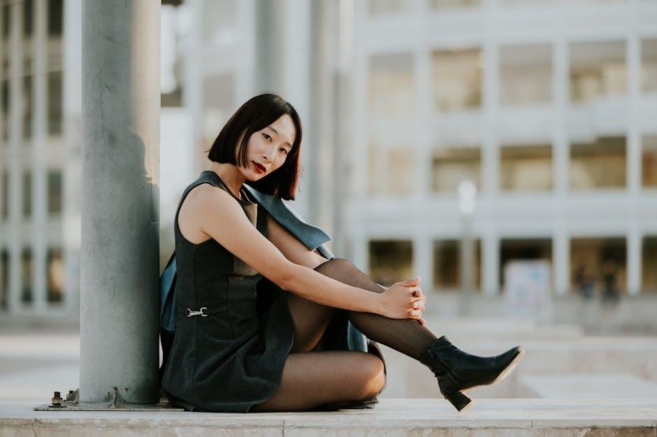 Il_successo_di_Sneex_e_il_look_di_Kathy_Bates_nIgsMkFK7O - Confidenze24 Source: Amar Preciado - pexels - Elegant woman in black dress sitting outdoors against modern architecture.