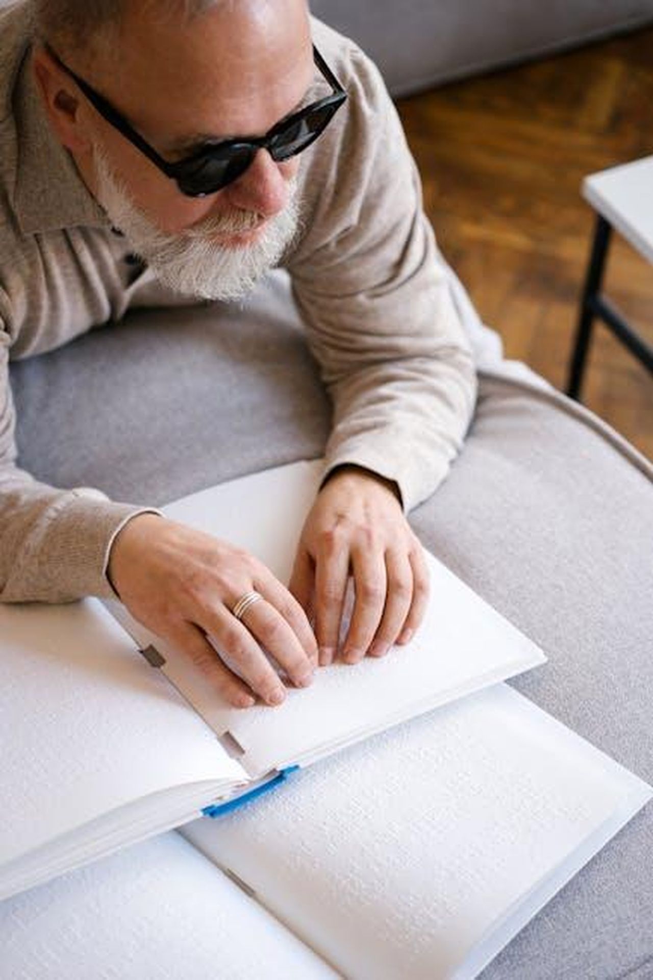 Il_supporto_dei_fan_per_la_famiglia_Siddiqui_KsarPTkL8X - Confidenze24 Source: Mikhail Nilov - pexels - Man wearing sunglasses reading a Braille book, representing disability support and education.