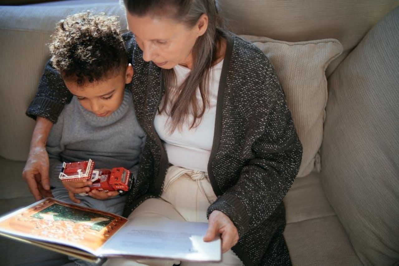 Il_trono_di_Tina_Cipollari_al_centro_dellattenzione_a_UD_LZpX0ll6Pp - Confidenze24 Source: Mikhail Nilov - pexels - A grandmother and grandson sharing a cozy reading moment on a sofa indoors.