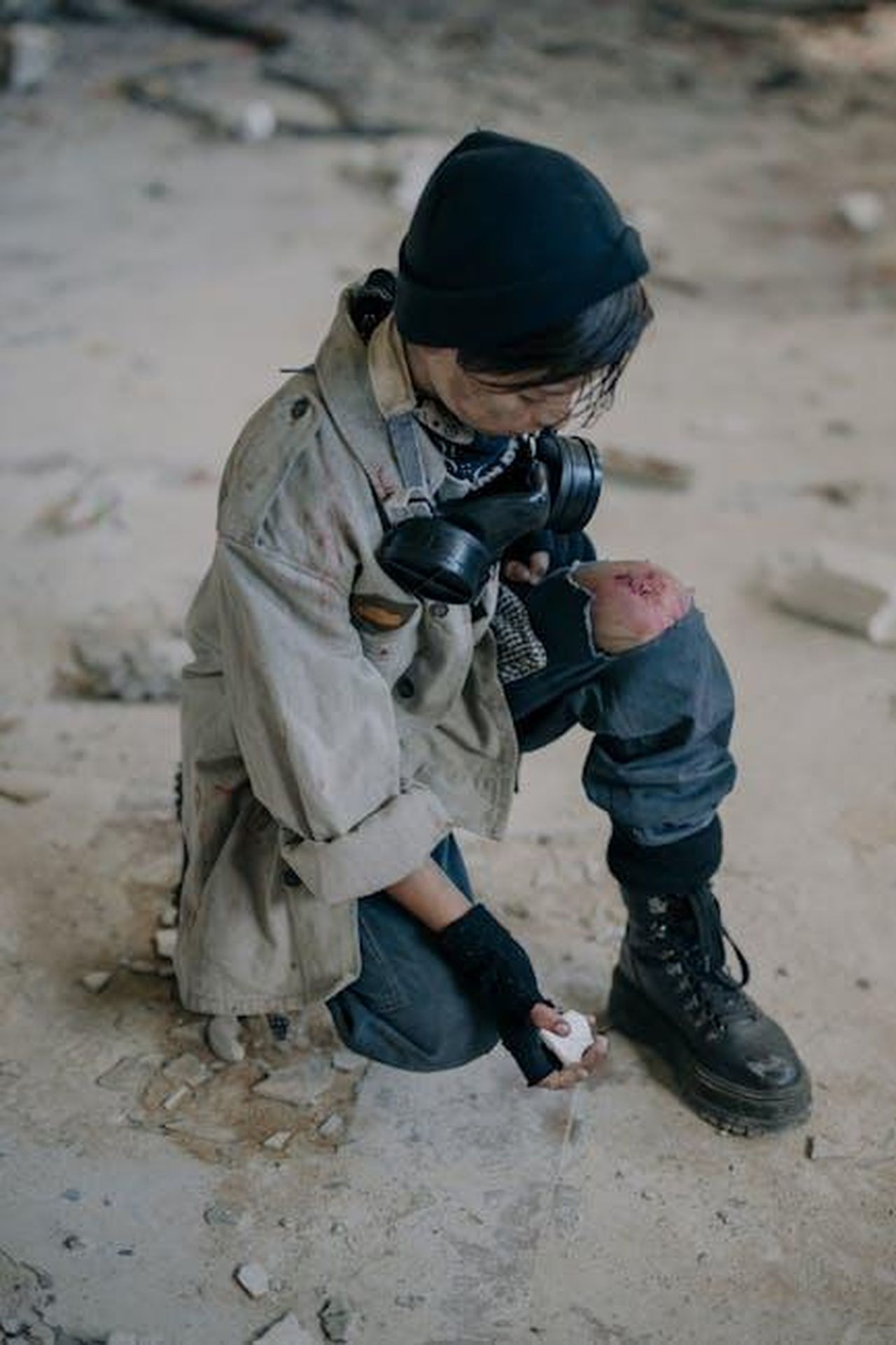 Il_web_scatenato_tra_teorie_e_vecchi_indizi_qzqQYiIXwH - Confidenze24 Source: cottonbro studio - pexels - A young person squats in a ruined urban environment wearing a mask.