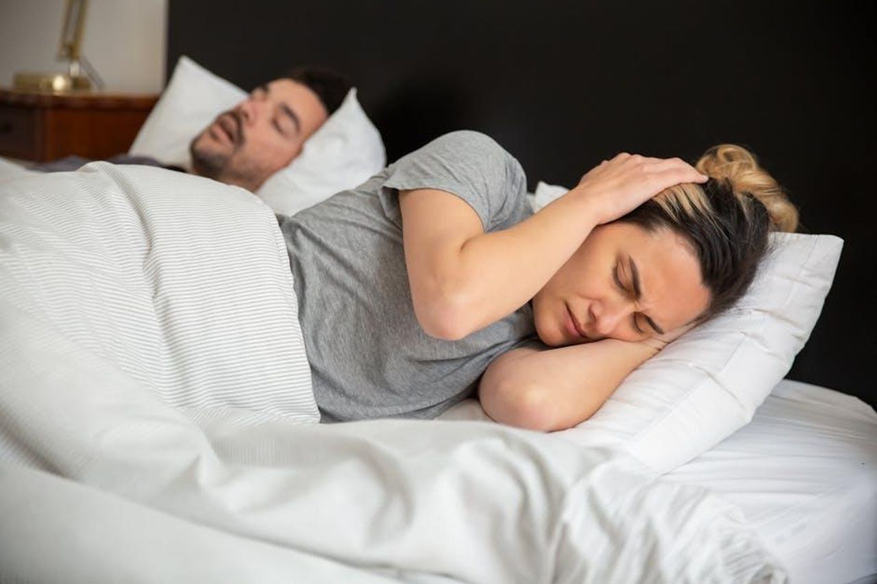 Il_web_si_divide_Chiara_e_Lorenzo_saranno_una_nuova_coppia_n5U2zW8hjC - Confidenze24 Source: Kampus Production - pexels - A woman looks frustrated in bed as her partner snores loudly, highlighting sleep disturbance issues.
