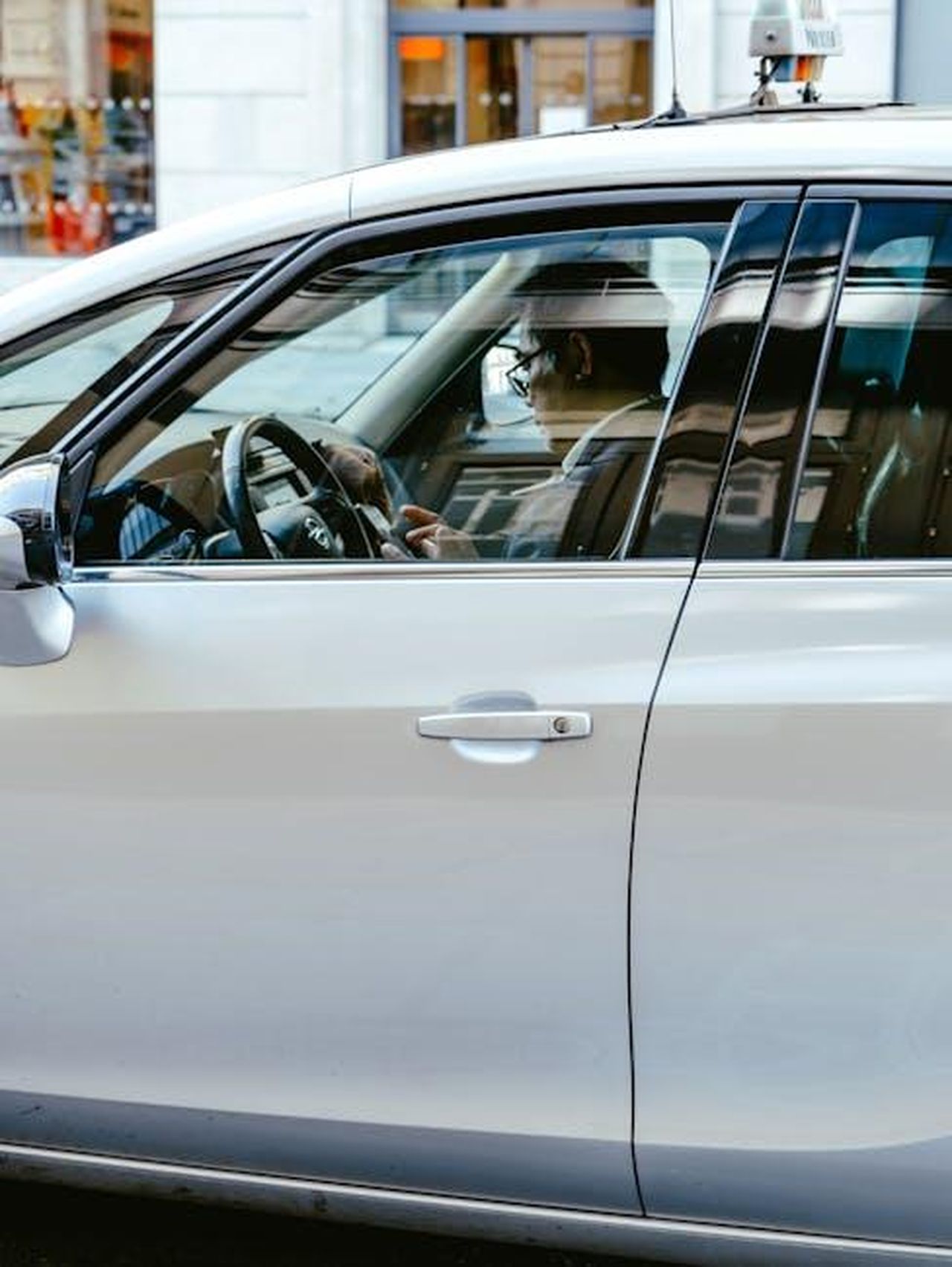 Implicazioni_legali_e_politiche_della_causa_n8BGBPY3wM - Confidenze24 Source: Mathias Reding - pexels - Side view of a man using a smartphone inside a car, showcasing distracted driving.