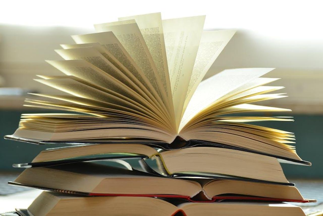 Indagini_in_corso_z5faS2aaXQ - Confidenze24 Source: Pixabay - pexels - A close-up of a stack of open books with pages fanned out, capturing a study atmosphere.