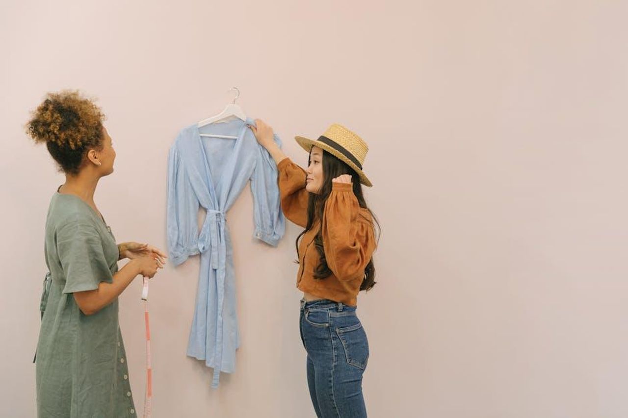 Jacqueline_Jossa_si_separa_da_In_The_Style_PaCkd6GrsU - Confidenze24 Source: Thirdman - pexels - Two women planning a design strategy in a clothing store, discussing a blue dress.
