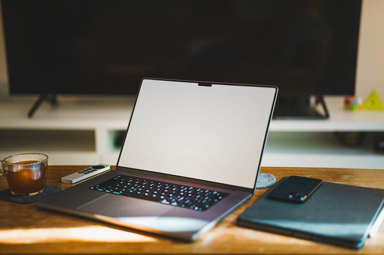 Jenna_Bush_Hager_e_i_suoi_coconduttori_ospiti_diFzZkNlPf - Confidenze24 Source: Jakub Zerdzicki - pexels - Contemporary home workspace with laptop, smartphone, and TV in a cozy setting.