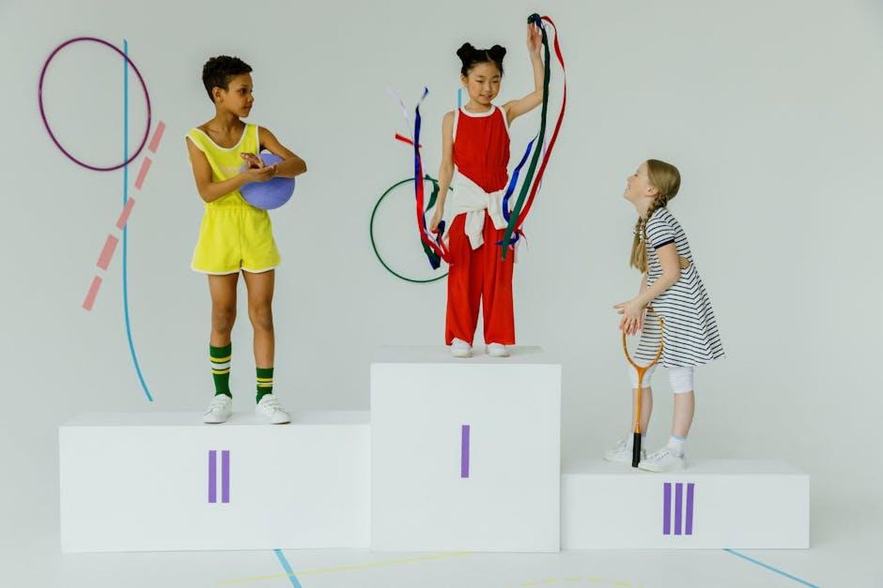 Jordan_Chiles_e_la_sua_controversia_olimpica_L1PIwTbA3z - Confidenze24 Source: cottonbro studio - pexels - Three happy children celebrating on a gymnastics podium with equipment.