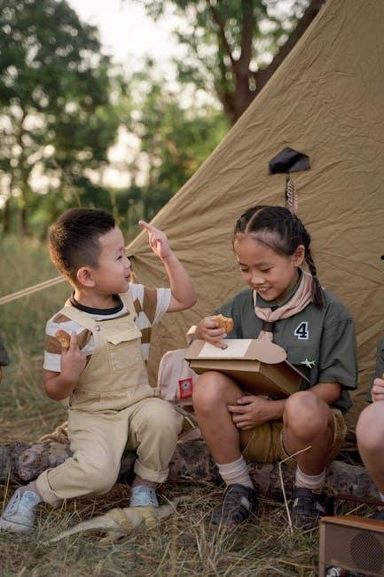 Kaavia_e_la_vendita_dei_biscotti_delle_Girl_Scouts_mGFSoEXUB4 - Confidenze24 Source: cottonbro studio - pexels - Two kids eat snacks together at a scout camp outside a tent.