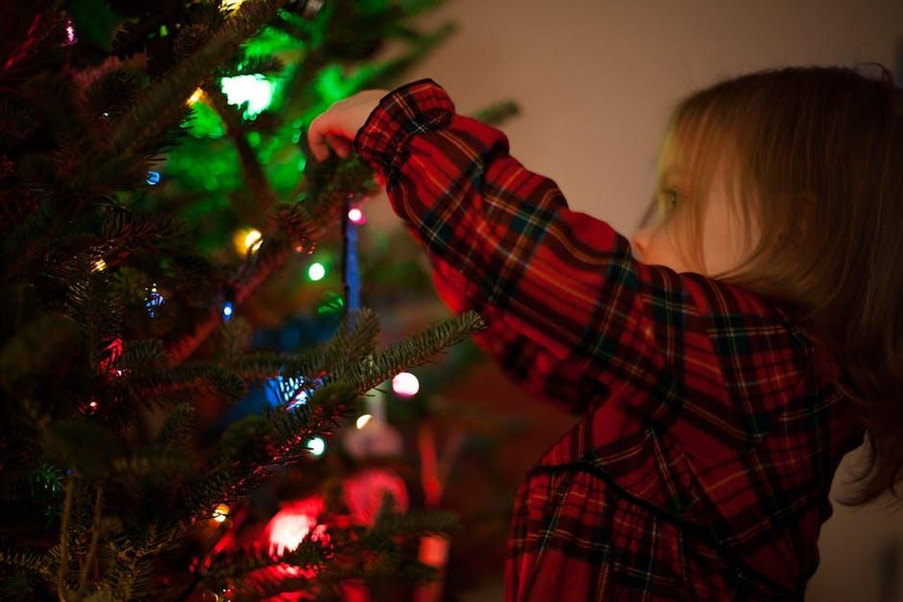 Kaavia_e_le_sue_performance_natalizie_jKhwah0y1S - Confidenze24 Source: Josh Willink - pexels - A young girl in plaid reaching to decorate a lit Christmas tree at home.