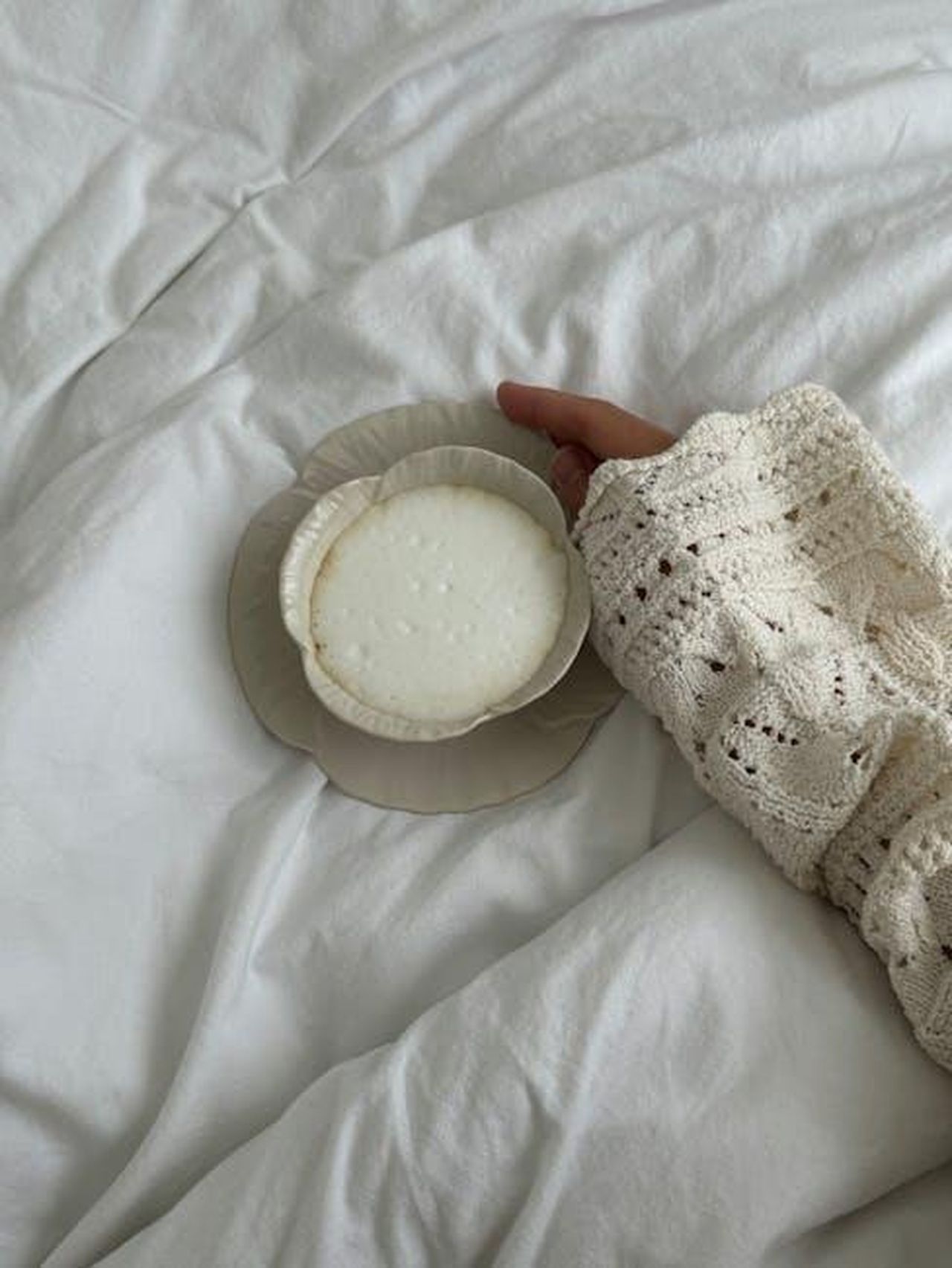 LOroscopo_settimanale_segno_per_segno_miglioramenti_per_Toro_sPuwos129z - Confidenze24 Source: Aljona Ovtšinnikova - pexels - A woman's hand holding a plate with a creamy dessert on a cozy white bedspread.