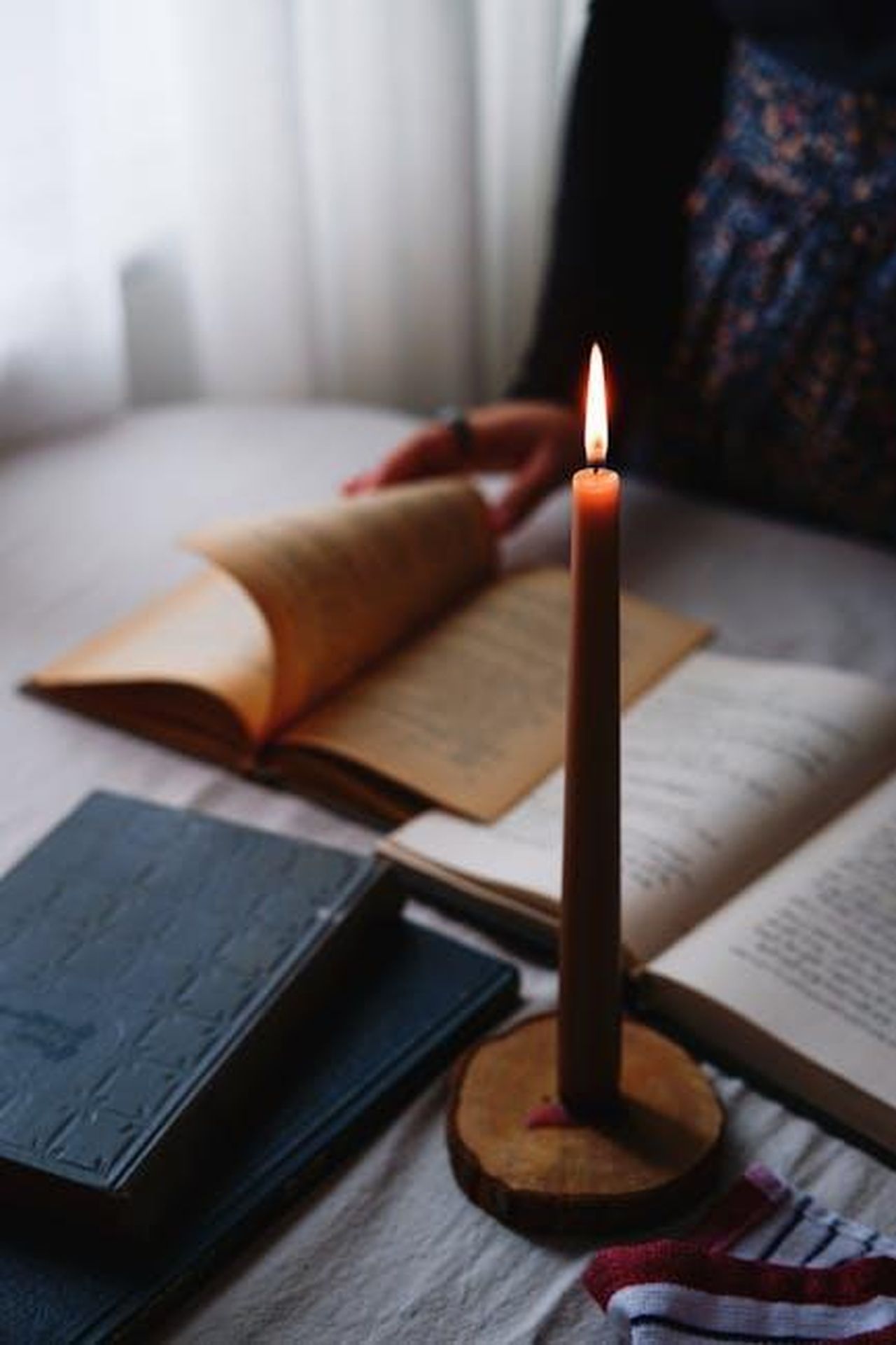 La_Storia_di_Wicked_Una_Nuova_Prospettiva_mexTMdZFu0 - Confidenze24 Source: beytlik - pexels - A cozy scene with books and a candle on a table, inviting to a relaxed reading session.