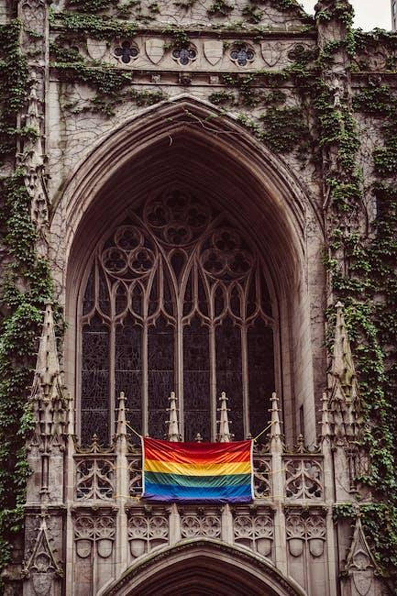 La_chiesa_come_rifugio_per_tutti_sz7twEMG1X - Confidenze24 Source: Ricky Esquivel - pexels - Gothic church facade in Chicago adorned with a rainbow flag promoting inclusivity.