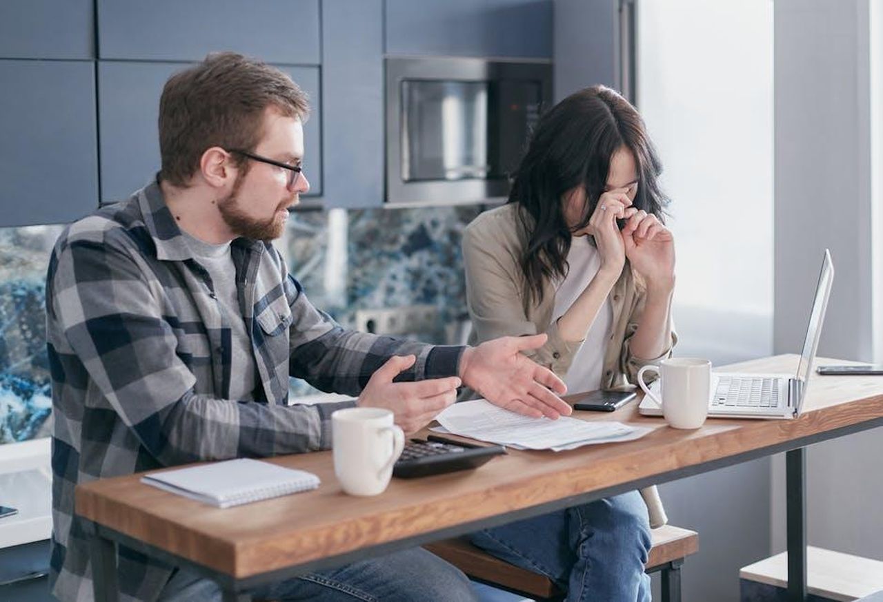 La_crisi_matrimoniale_3aYUWyB1B4 - Confidenze24 Source: Mikhail Nilov - pexels - A couple sitting at a table indoors, visibly stressed while discussing bills and finances.