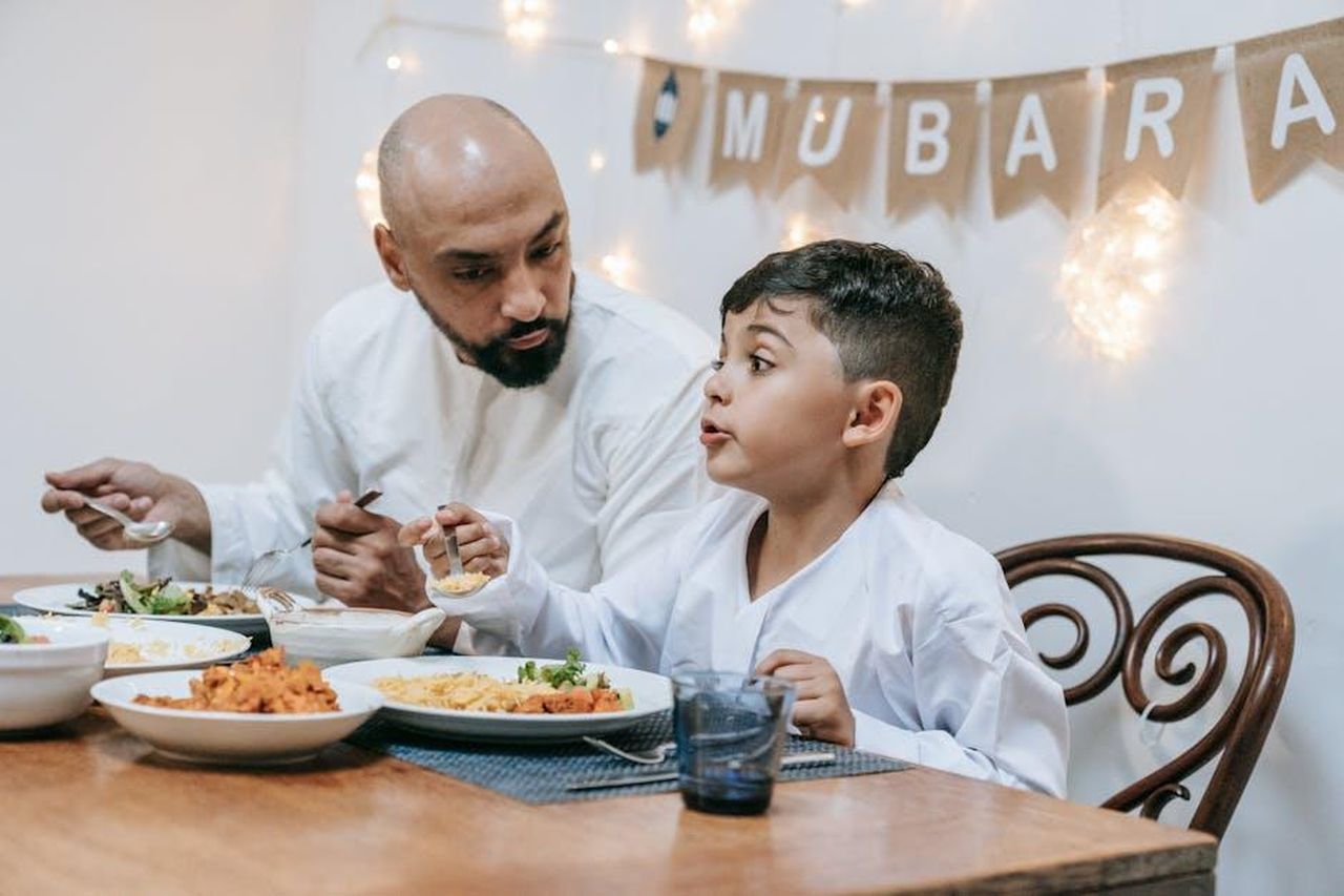 La_critica_alla_spettacolarizzazione_del_Festival_di_Sanremo_SX9MCegzyc - Confidenze24 Source: Timur Weber - pexels - Father and son enjoy a festive meal during Eid Mubarak celebration.