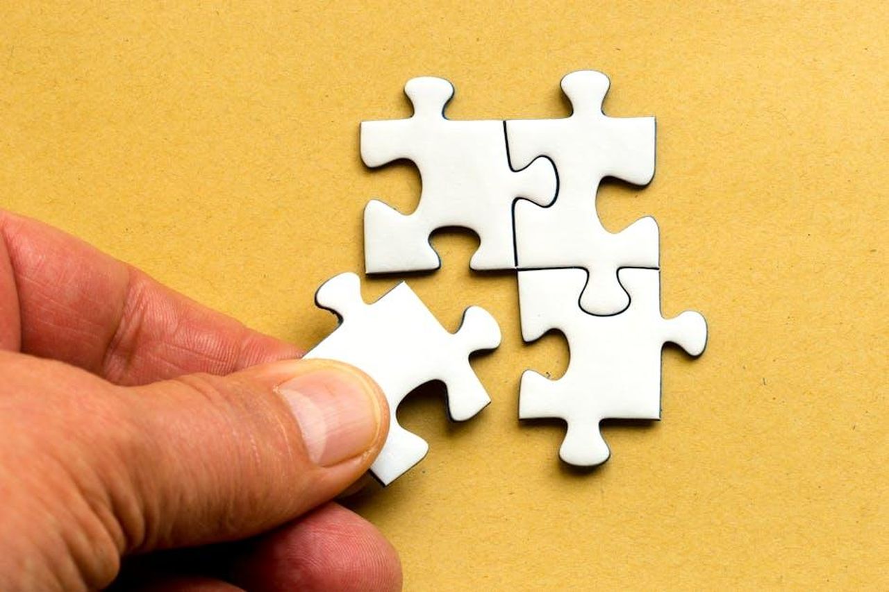 La_decisione_finale_di_Giulia_fZJzWgwcor - Confidenze24 Source: Mike van Schoonderwalt - pexels - Close-up of a hand completing a white jigsaw puzzle on a yellow background.