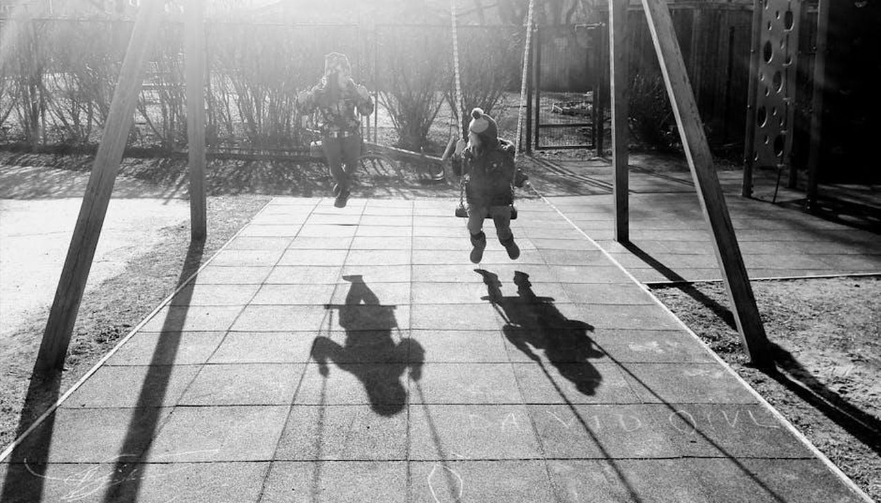 La_differenza_tra_Meghan_e_Kate_lkG7U1qhS8 - Confidenze24 Source: Pille Kirsi - pexels - Children playing joyfully on swings, casting shadows in a sunny park.