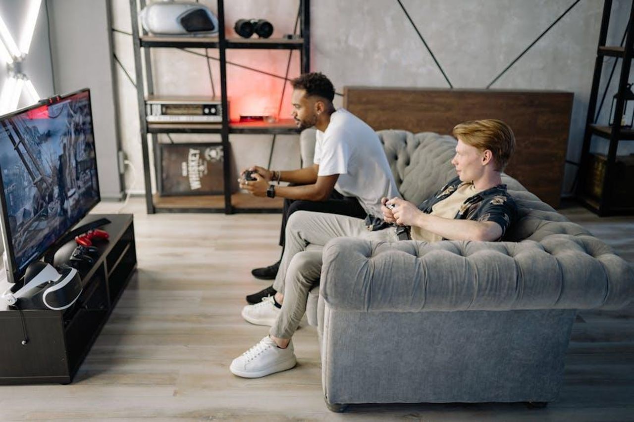La_fiction_di_Rai_1_sfider_lappuntamento_serale_con_il_Grande_Fratello_18_LawbFTmHt1 - Confidenze24 Source: Yan Krukau - pexels - Two adult men playing video games on a couch, enjoying leisure time indoors.