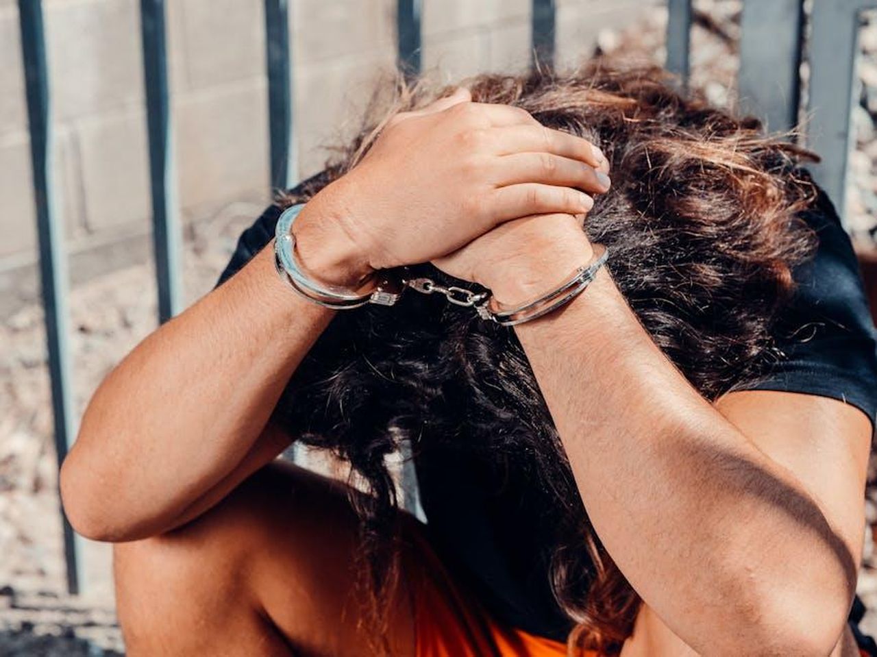 La_parola_di_Oyku_non_avr_valore_legale_Ip91rTgxHS - Confidenze24 Source: Kindel Media - pexels - A man in handcuffs sits outdoors, covering his face in distress.