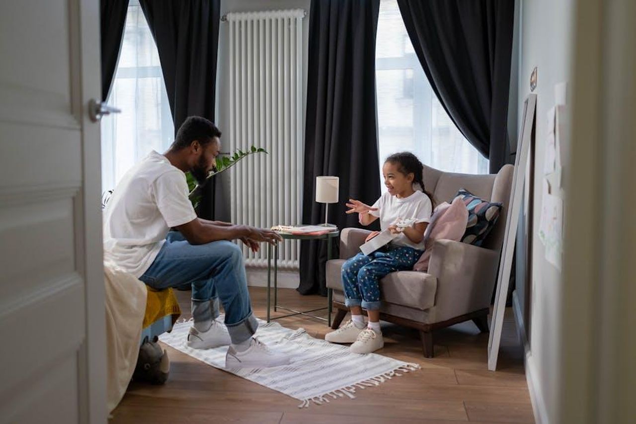 La_pressione_del_cognome_Morandi_e_i_figli_Prh0uRwfMu - Confidenze24 Source: cottonbro studio - pexels - A father and daughter engage in conversation in a cozy indoor setting, fostering family connection.