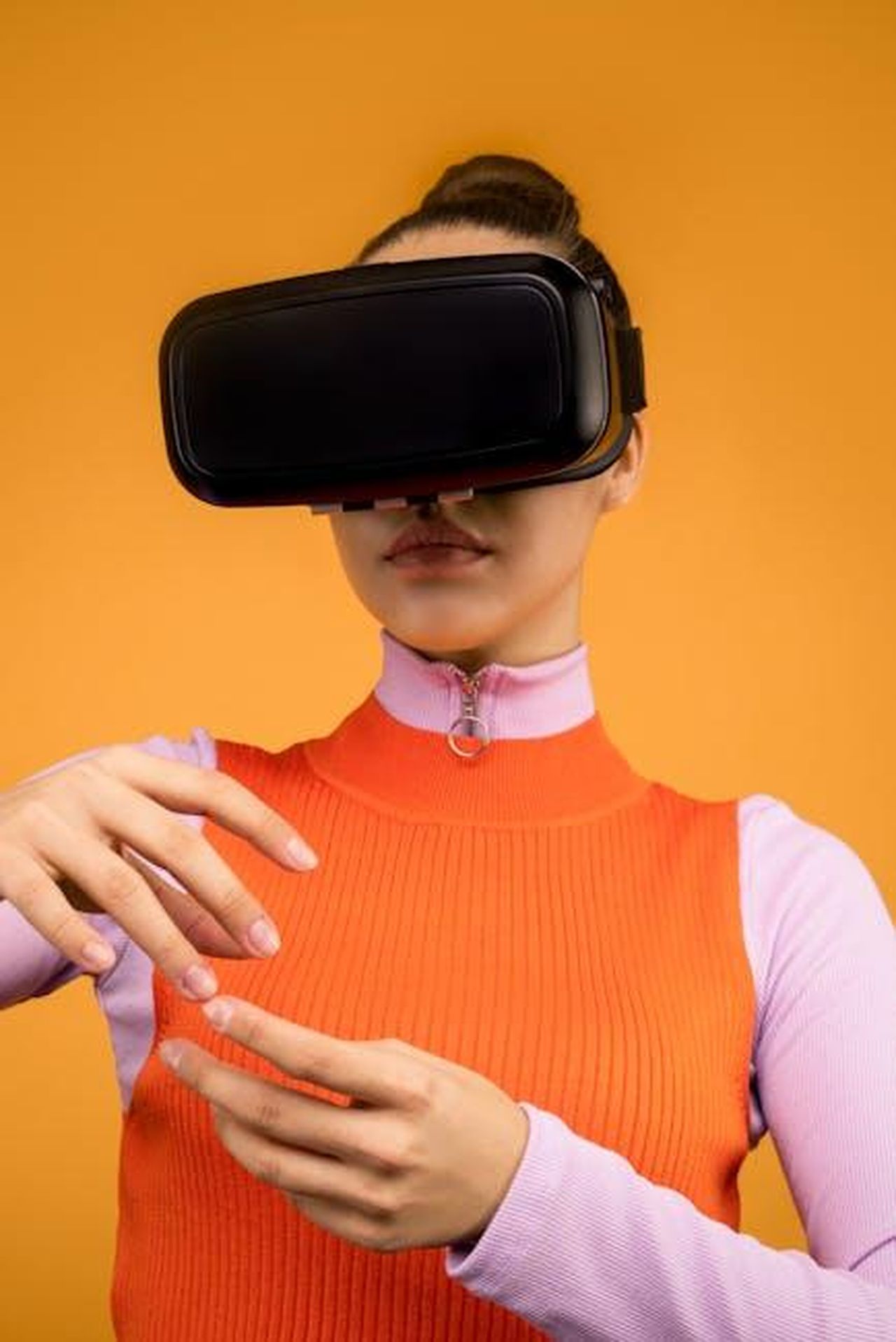 La_reazione_dei_media_e_del_pubblico_Og5HiWSoct - Confidenze24 Source: Sound On - pexels - Woman immersed in virtual reality wearing VR headset, gesturing against orange background.