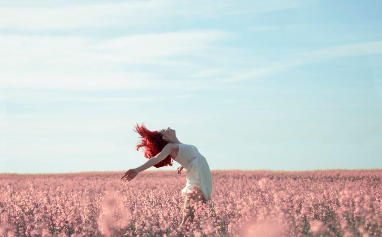 La_reazione_di_Johnson_alla_sua_liberazione_RKdsMII8wR - Confidenze24 Source: Olga - pexels - Woman with red hair in a white dress expressing freedom in a vibrant summer field.