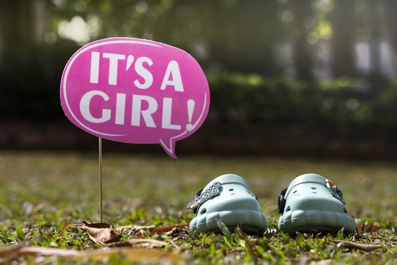 La_reazione_di_Meghan_alla_situazione_tEgXRfEc1E - Confidenze24 Source: Anil Sharma - pexels - Pink 'It's a Girl!' sign next to baby shoes on a grassy lawn background.